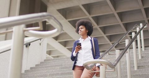 Businesswoman Walking Down Steps Holding Smartphone Confidently