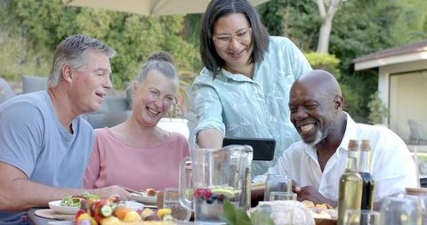 Diverse friends enjoying outdoor luncheon viewing smartphone
