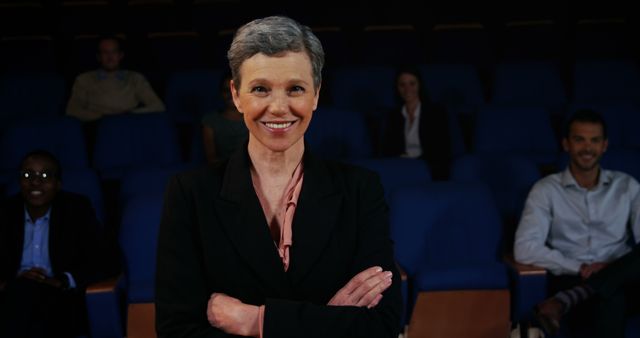 Businesswoman presenting confidently in front of colleagues in an auditorium. Great for illustrating concepts of leadership, professional presentations, teamwork, and corporate training events.