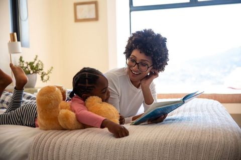 Mother and daughter reading together in sunlit bedroom