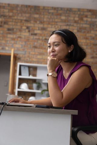 Professional Woman in Modern Studio Using Laptop Thoughtfully