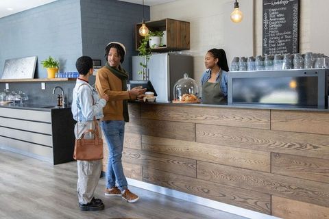 African american couple ordering coffee at modern cafe counter with smiling barista