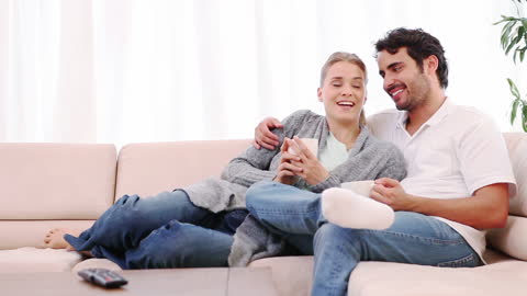 Happy Couple Relaxing on Sofa with Coffee and Conversation