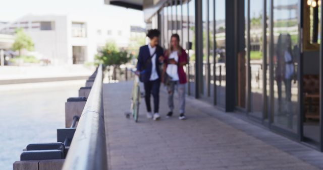 Young professionals walking and talking outdoors near a modern office building. Ideal for use in corporate communications, workplace wellness, teamwork, collaboration, urban lifestyle, and business culture materials.