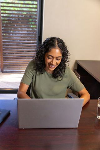 Smiling Woman Typing on Laptop in Cozy Home Office