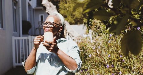 Senior Woman Enjoying Coffee in Sunlit Garden