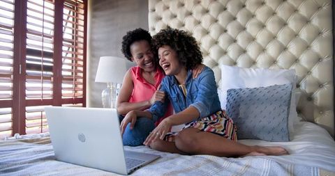 Happy Diverse Couple Enjoying Movie on Laptop in Cozy Bedroom