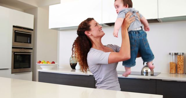 Mother Lifting Baby in Modern Kitchen - Download Free Stock Images Pikwizard.com