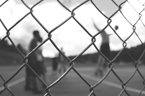 Blurred Street Basketball Game through Chain Link Fence