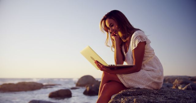 Woman on Rocky Beach Using Laptop during Sunset - Download Free Stock Images Pikwizard.com