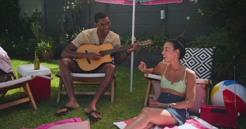 Friends enjoying music and relaxation in a sunny backyard