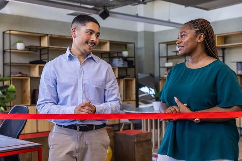 Coworkers celebrating ribbon cutting ceremony in modern office