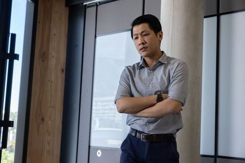 Pensive asian professional standing in modern office environment