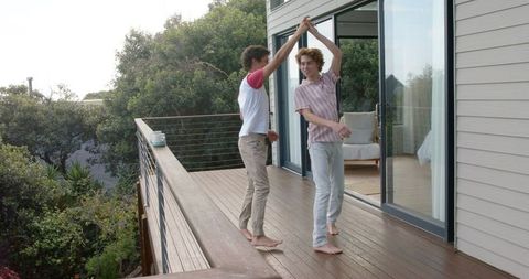 Joyful Same-Sex Couple Dancing on Sunlit Balcony