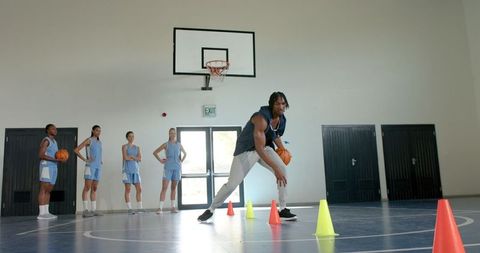 Group of basketball players practicing dribbling skills indoors