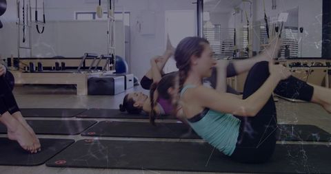 Women performing pilates core exercises on mats in bright reformer studio