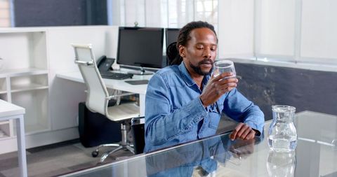 Man Evualating Glass of Water in Office Environment