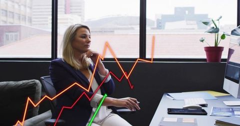 Executive Woman Analyzing Colorful Line Graphs at Desk in Modern Urban Office