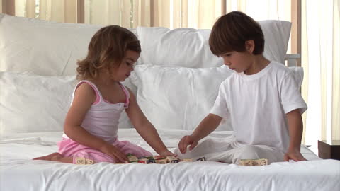 Children Quietly Playing with Blocks on Cozy Bed at Home