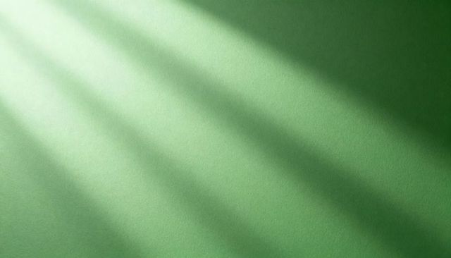 Diagonal blind shadows casting across textured green wall with soft striped gradient