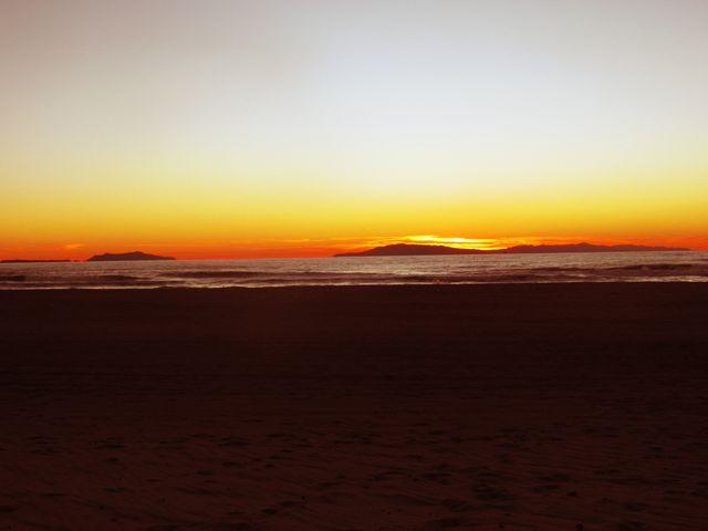 Serene Beach Sunset with Glowing Horizon and Silhouetted Islands - Download Free Stock Photos Pikwizard.com