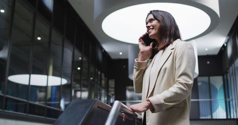 Smiling Businesswoman on Phone in Modern Office Lobby