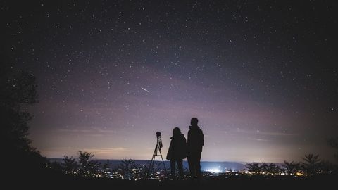 Stargazing Couple Watching Night Sky with Telescope Outdoors