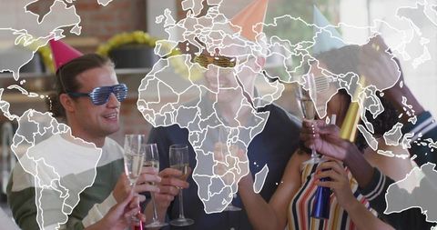 Global celebration friends cheering with champagne and party hats in urban loft with map overlay
