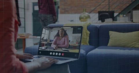 Working remotely on laptop from living room couch while video calling colleague
