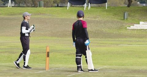 Cricketers Holding Bat on Suburban Pitch Near Stumps