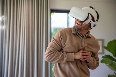 Mature man enjoying virtual reality headset in cozy living room with natural light