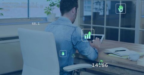 Man wearing light blue denim shirt tapping tablet at desk with analytics overlays