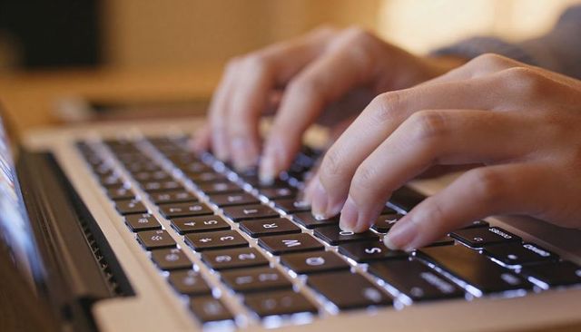Close-Up Hands Typing on Backlit Laptop Keyboard for Remote Work and Productivity