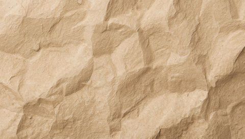 Crumpled kraft paper texture showing creases fibers speckles and warm beige wrinkled surface