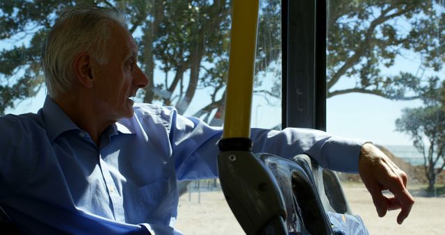 Thoughtful senior caucasian man sitting in city bus looking through window. Transport, city living and lifestyle, unaltered.
