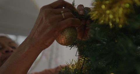Senior woman decorating christmas tree with ornaments