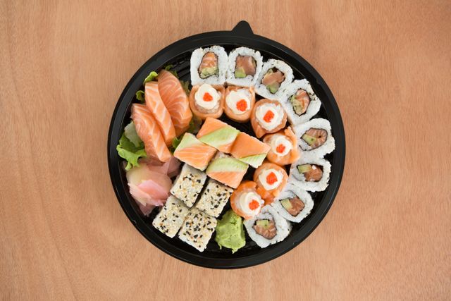 Various sushi rolls in platter on wooden background