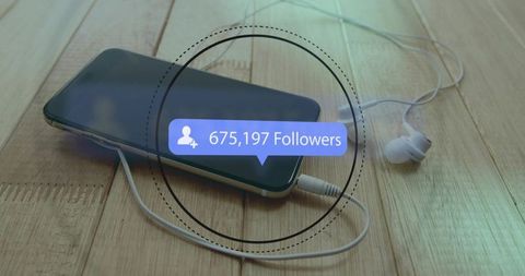 Smartphone with wired earbuds and social media followers notification on wood surface