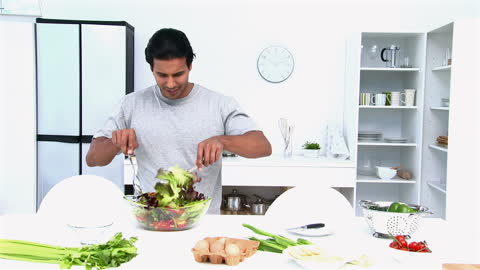 Man Preparing Fresh Salad for Lunch in Modern Kitchen