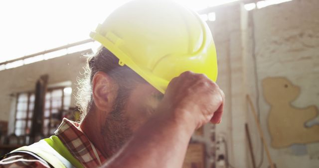 Carpenter Adjusting Hard Hat in Sunny Workshop - Download Free Stock Images Pikwizard.com