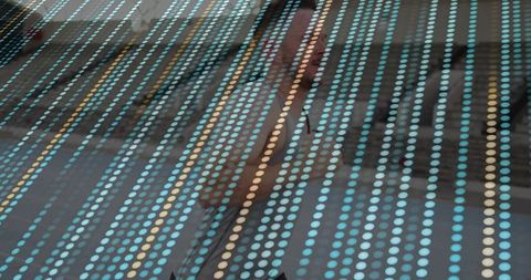 Businessman walking behind dotted panel in urban scene