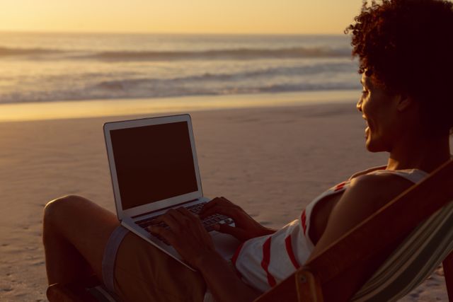 Young man using laptop while relaxing in a beach chair on the beach