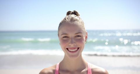 Joyful Young Woman Smiling Brightly by the Ocean