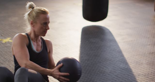 Fit caucasian woman performing abs exercise with medicine ball at the gym. sports, training and fitness concept