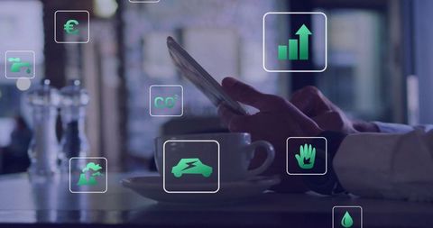 Executive tapping tablet in cafe using digital green sustainability and finance icons