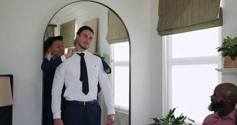 Groom Adjusting Suit with Friends Before Wedding Ceremony