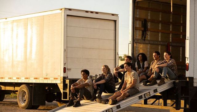 Delivery team sitting and relaxing on loading ramp at golden hour, casual workwear