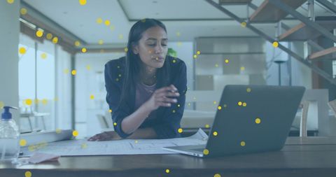 Biracial woman using laptop for business planning in office