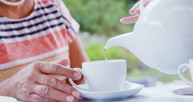 Senior Woman Pouring Tea from White Teapot into Teacup - Download Free Stock Images Pikwizard.com