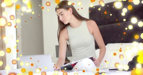 Young woman working remotely on laptop in cozy bedroom with soft bokeh hexagon glow